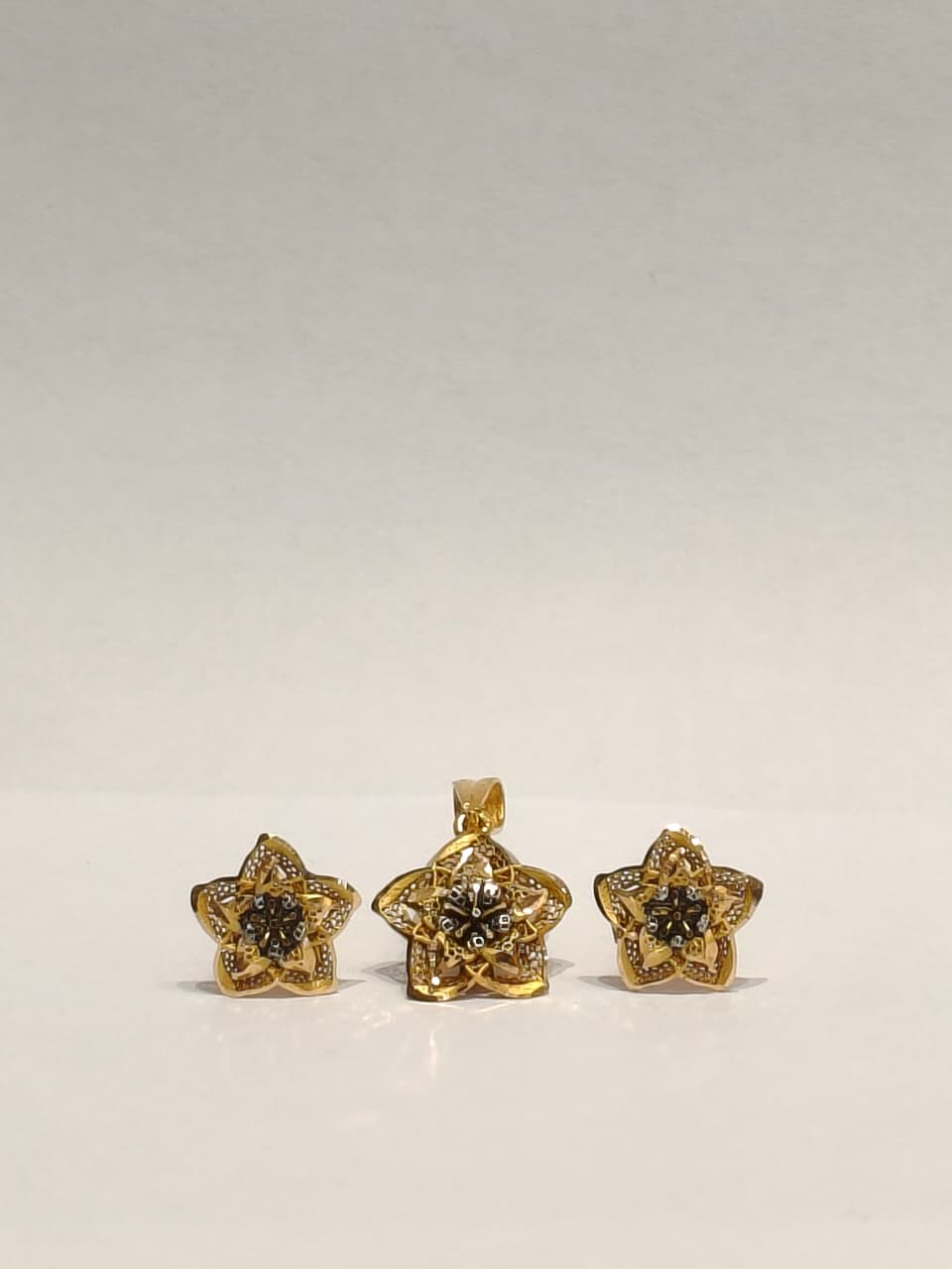 Gold star-shaped jewelry set on a light gray background